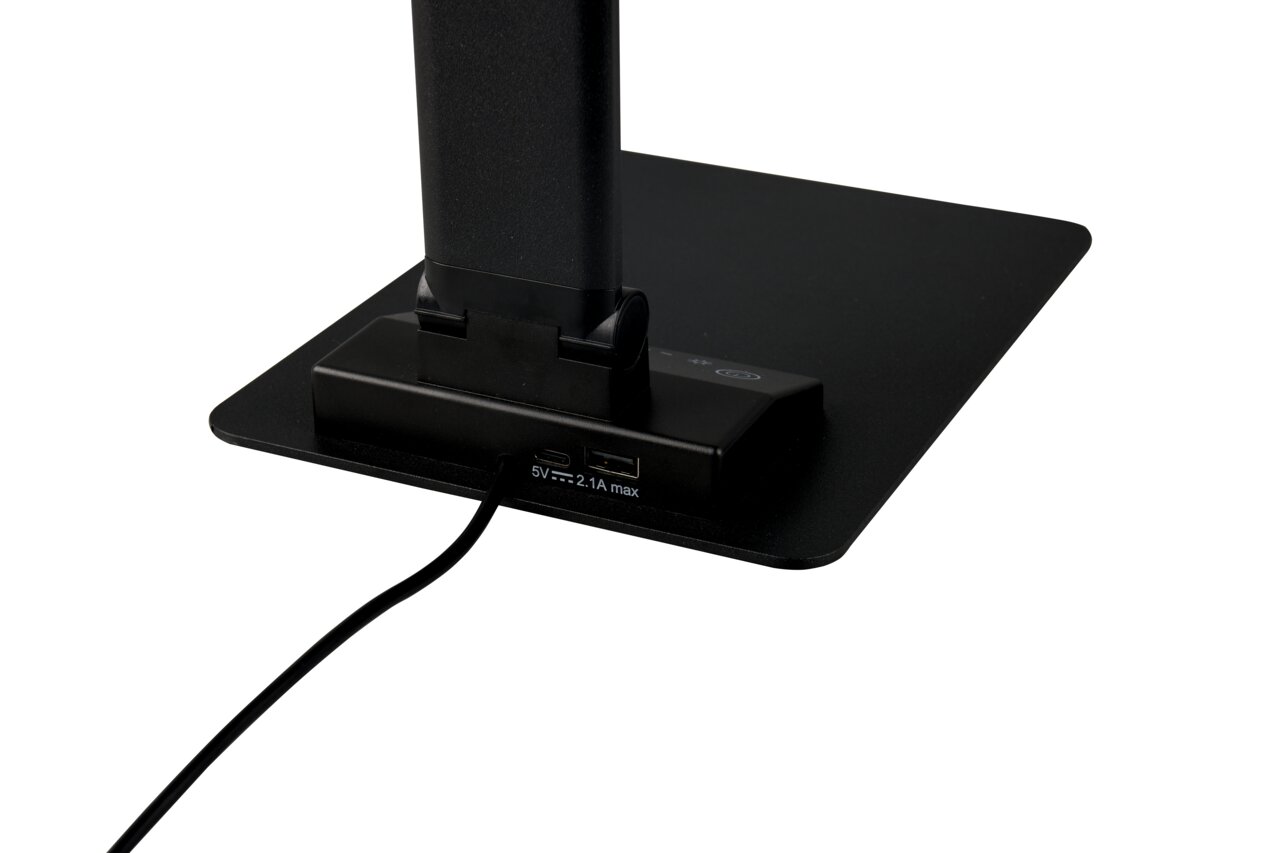 Close-up van de voet van een zwarte TRAVIS-tafellamp met USB-aansluitingen en netsnoer, gezien vanaf de zijkant