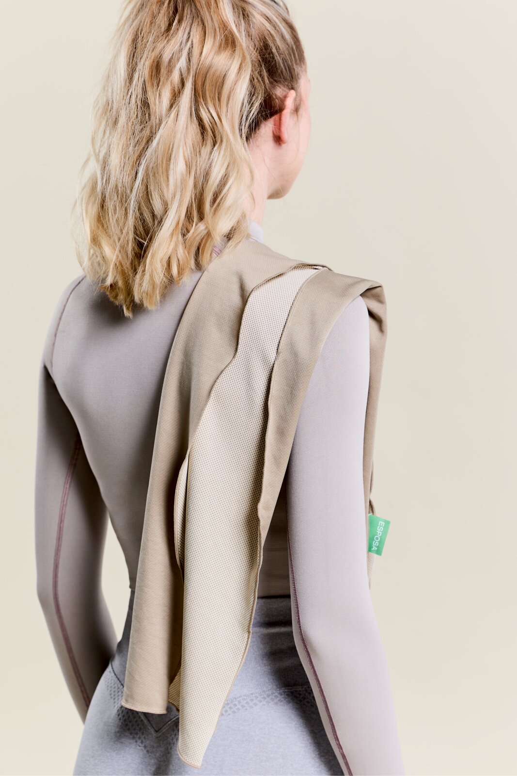 Achterkant van een persoon met een beige sporthanddoek over de schouder.