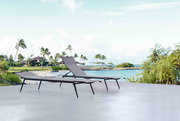 Zwei moderne Sonnenliegen auf einer Terrasse mit Blick auf einen tropischen Strand und Palmen im Hintergrund.
