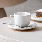 Weiße Kaffeeuntertasse Afina 14,2cm mit Tasse und Löffel, seitliche Perspektive