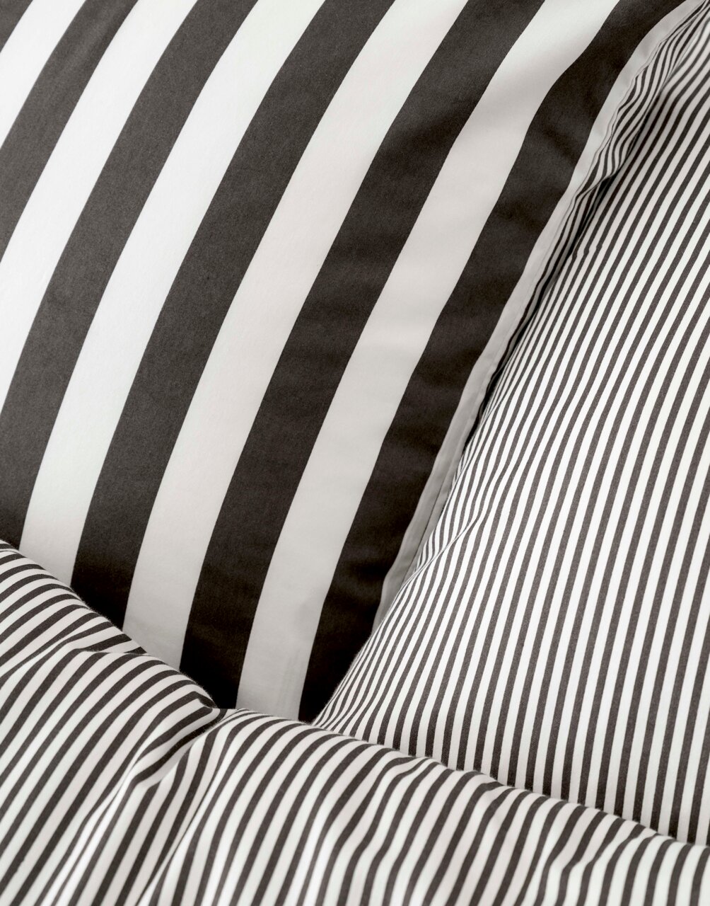 Nahaufnahme von gestreifter Bettwäsche in Schwarz-Weiß mit unterschiedlichen Streifenmustern.
