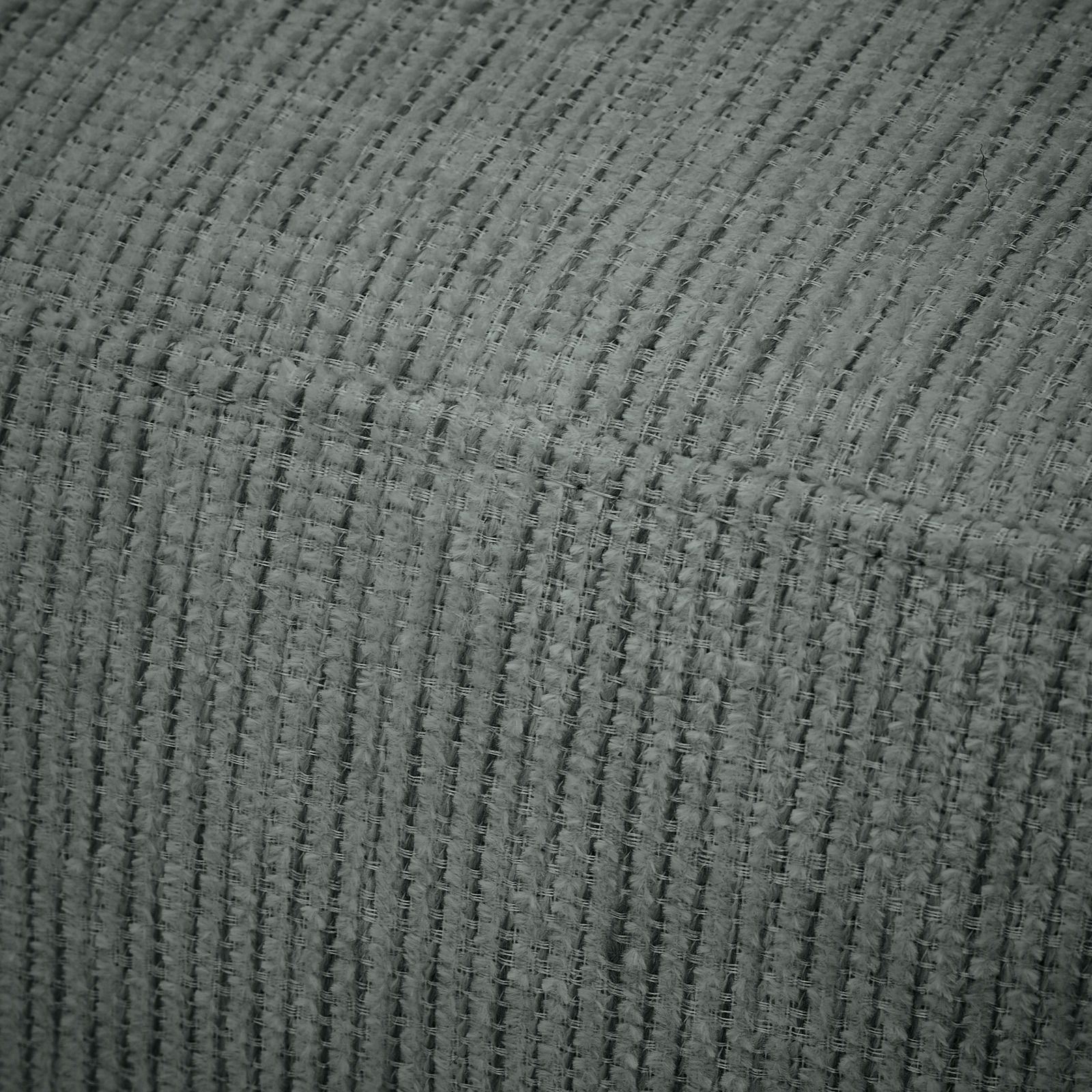 Nahaufnahme einer grauen, strukturierten Stoffoberfläche einer Recamiere, die die Textur und das Material des Möbelstücks zeigt.