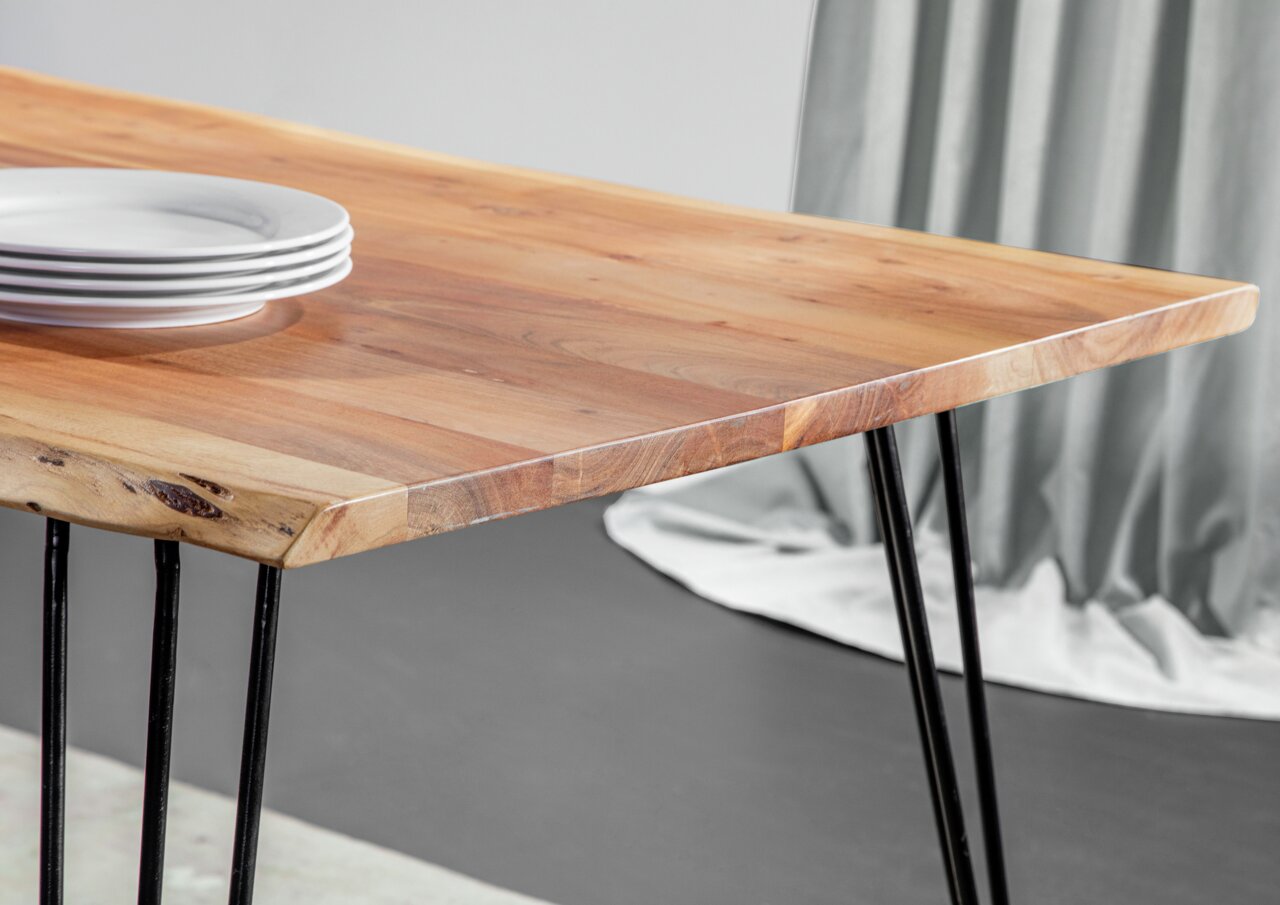 Nahaufnahme eines Esstisches mit Holzplatte und schwarzen Metallbeinen, seitliche Perspektive