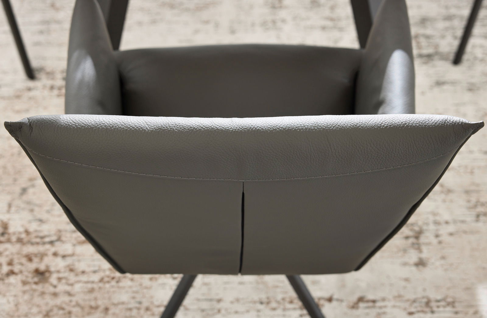 Rückansicht eines grauen Armlehnstuhls mit gepolstertem Lederbezug und modernen Metallbeinen.