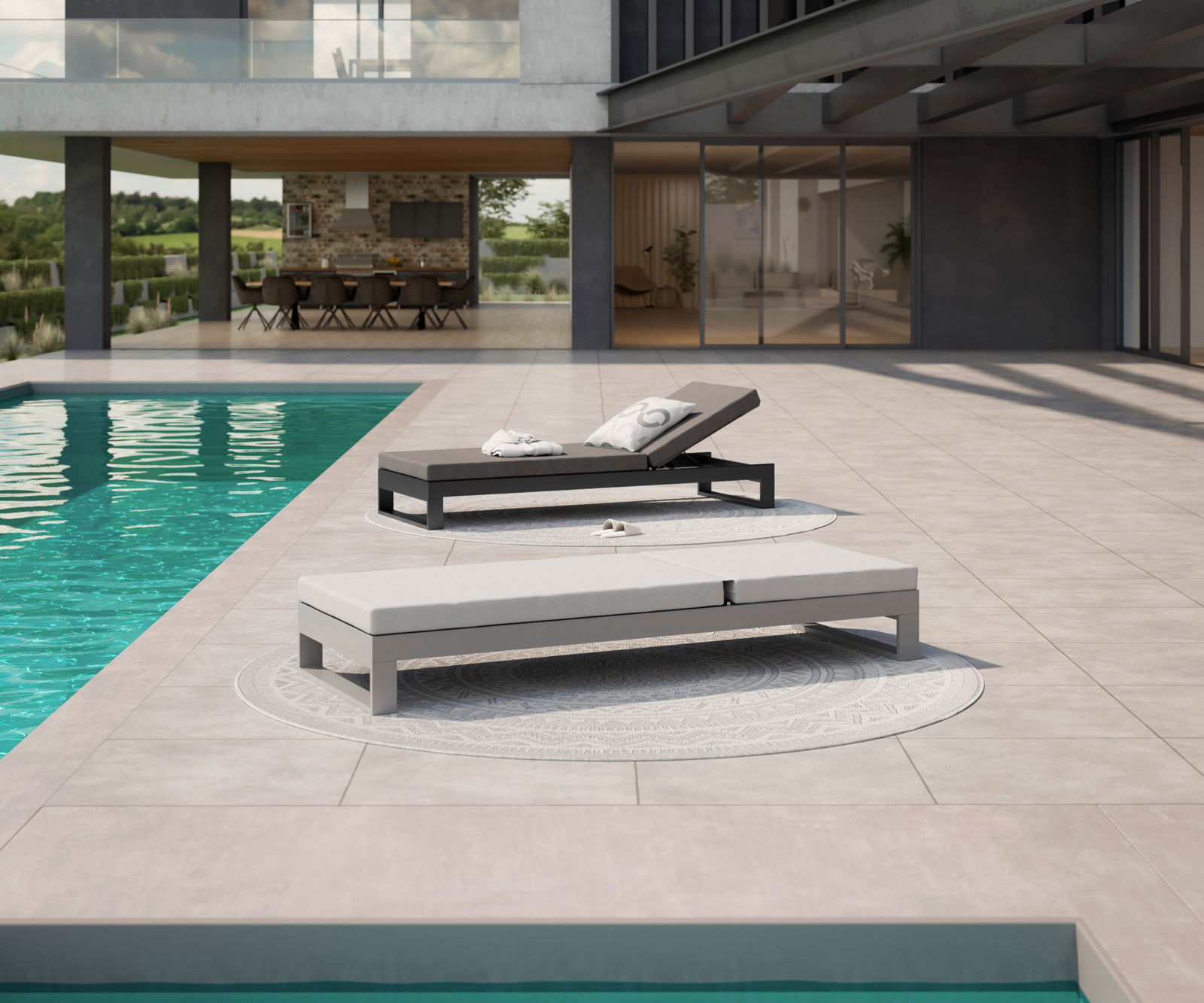Zwei moderne Sonnenliegen auf einer Terrasse neben einem Pool, eine in Schwarz und die andere in Grau, mit Blick auf ein modernes Gebäude im Hintergrund.