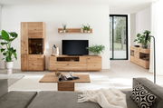 Wohnzimmeransicht mit der Linea Natura Wandkombination GEORGIA in hellem Holz, bestehend aus einem hohen Schrank, einem TV-Board und einem Regal, dekoriert mit Pflanzen und modernen Accessoires.