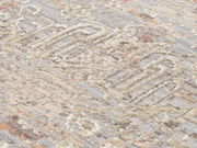 Nahaufnahme eines Designer Teppichs mit abstraktem Muster in Beige- und Grautönen, seitliche Perspektive