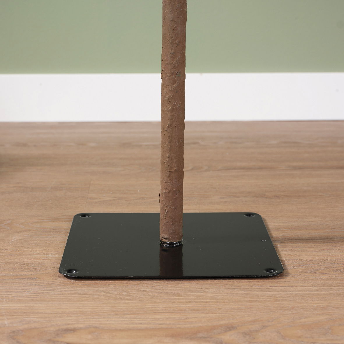 Nahaufnahme eines Baumstamms auf einer schwarzen Metallplatte, auf einem Holzboden stehend.