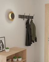 Goldene Wandleuchte TOCINA in einem modernen Flur, seitliche Perspektive.