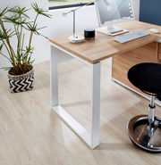 Moderner Schreibtisch mit Holzplatte und weißen Metallbeinen, seitliche Perspektive, mit Computer, Lampe und Pflanze dekoriert.