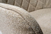 Nahaufnahme eines beige gepolsterten Drehstuhls mit texturierter Stoffoberfläche und gestepptem Muster, seitliche Perspektive.