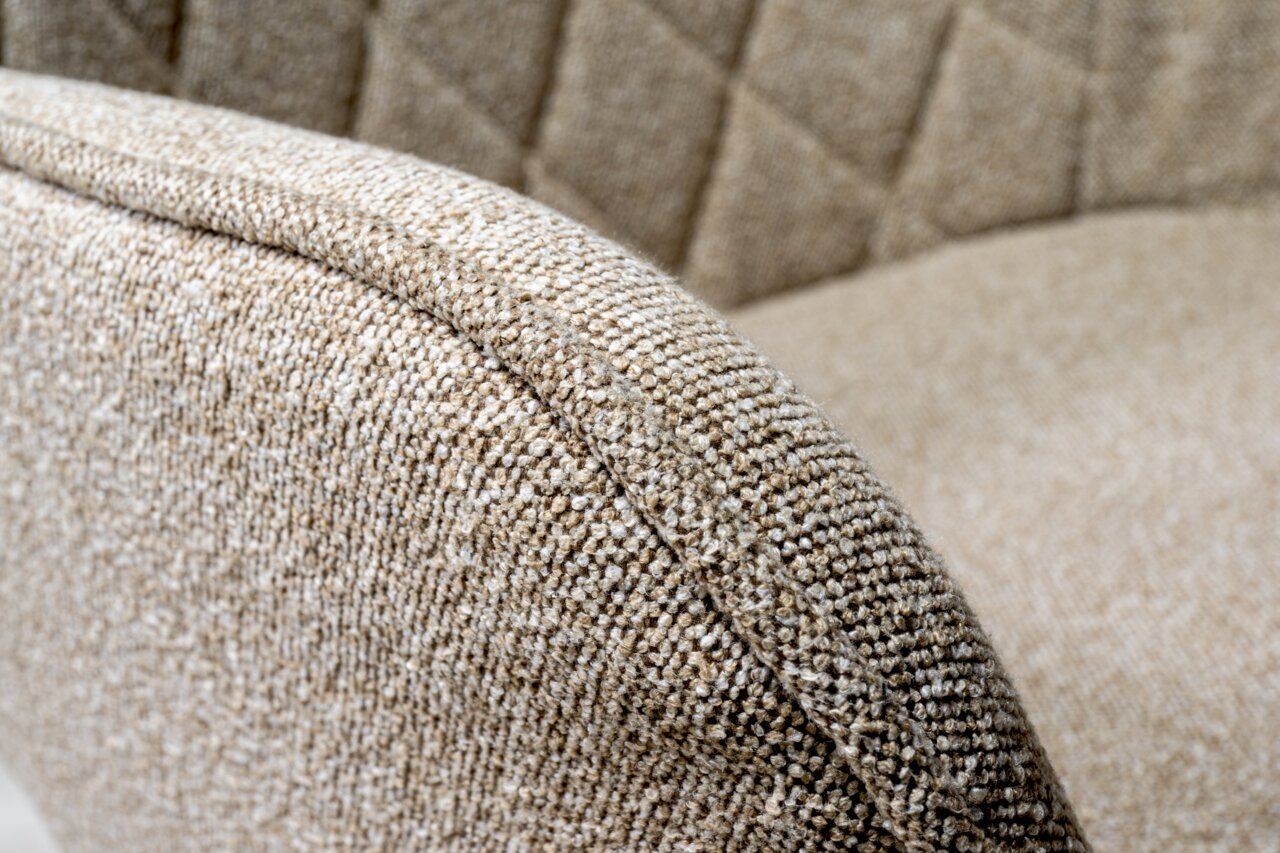 Nahaufnahme eines beige gepolsterten Drehstuhls mit texturierter Stoffoberfläche und gestepptem Muster, seitliche Perspektive.
