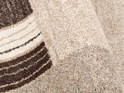 Nahaufnahme eines beigen Teppichs mit braunen Streifen, perspektivisch von der Seite aufgenommen.