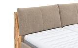 Nahaufnahme eines Polsterbetts mit beigem Kopfteil und weißer Matratze, seitliche Perspektive
