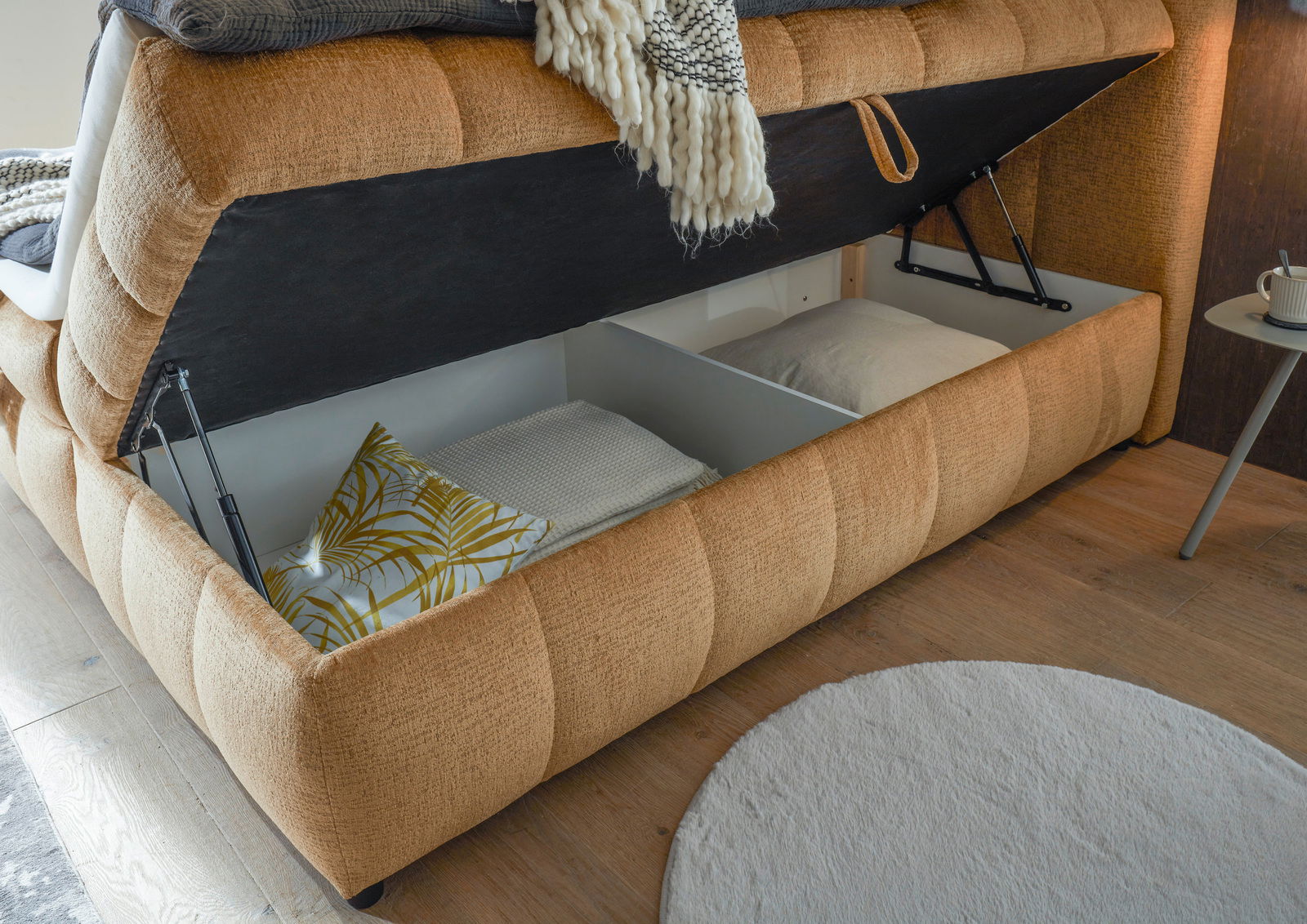 Boxbett mit geöffnetem Stauraum, seitliche Perspektive, zeigt Kissen und Decken im Inneren.