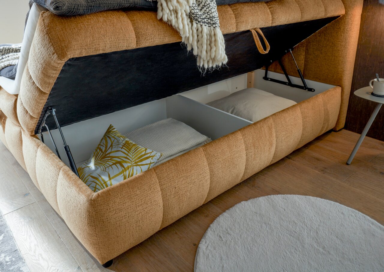Boxbett mit geöffnetem Stauraum, seitliche Perspektive, zeigt Kissen und Decken im Inneren.