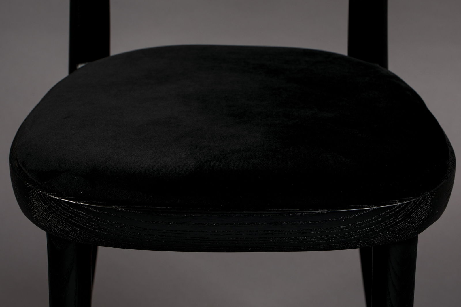 Nahaufnahme eines schwarzen Stuhlsitzes mit samtiger Oberfläche, von vorne betrachtet.
