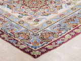 Nahaufnahme eines Orientteppichs mit detailliertem floralen Muster in Rot, Grün, Blau und Beige, von oben fotografiert.