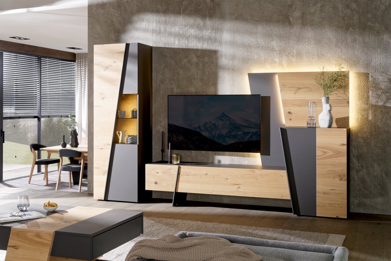 Moderne Wohnwand in Holzoptik mit grauen Akzenten, frontal fotografiert, mit integriertem TV und dekorativer Beleuchtung.