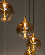 Moderne Hängeleuchte mit mehreren goldenen, kugelförmigen Lampenschirmen, seitliche Perspektive