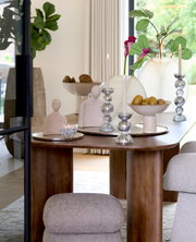 Elegante Vase auf einem Tisch, umgeben von dekorativen Elementen wie Kerzenhaltern und Schalen, mit Blick auf eine moderne, stilvolle Inneneinrichtung.