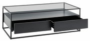 Moderner Couchtisch mit Glasplatte und zwei offenen Schubladen, seitliche Perspektive.