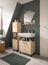 Moderne Badkombination mit Holzoptik, bestehend aus einem Waschbecken mit Unterschrank, einem hohen Schrank und einem Spiegel mit Ablage, seitliche Perspektive.