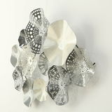 Metallisches Wandobjekt mit organischen Formen und filigranen Mustern, seitliche Perspektive