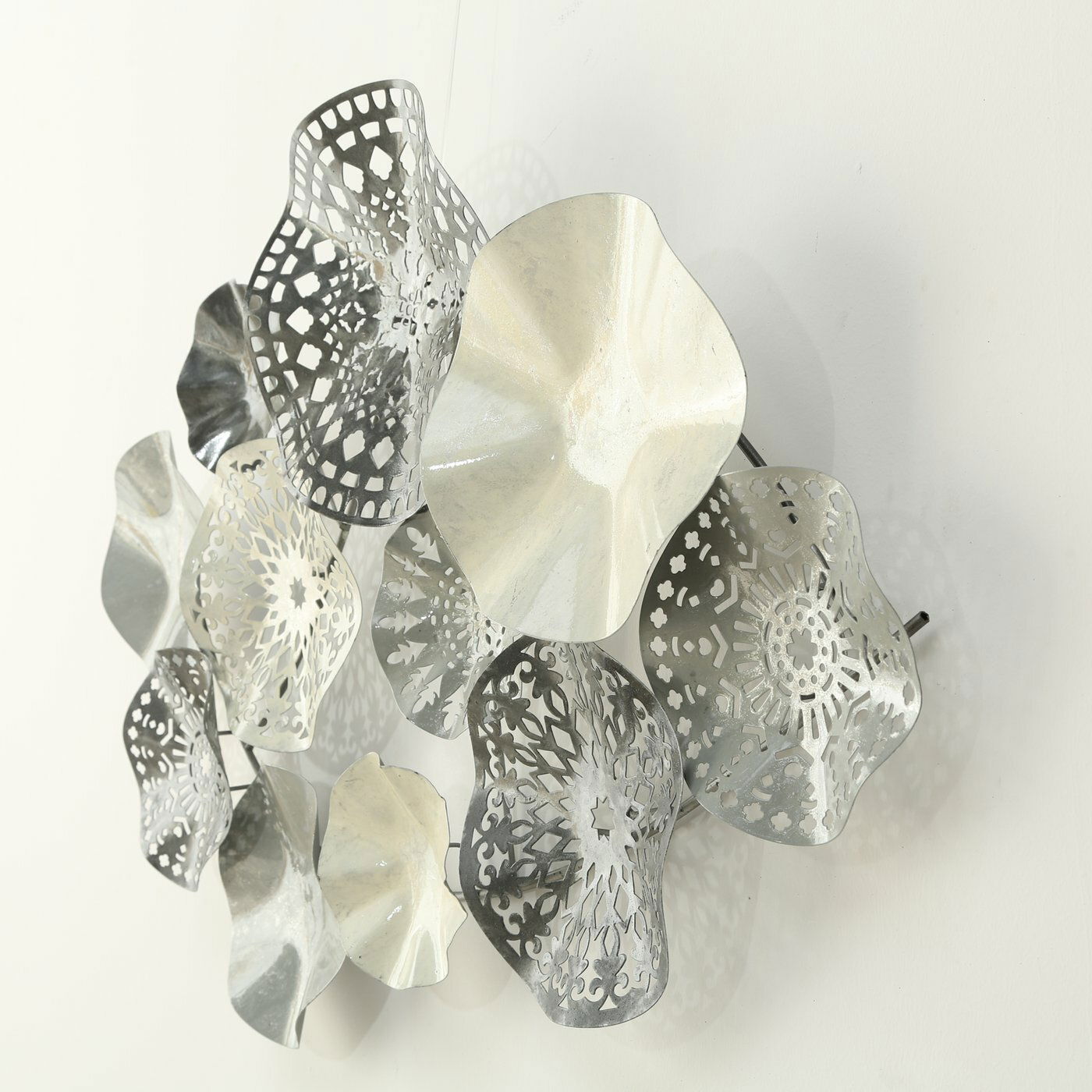 Metallisches Wandobjekt mit organischen Formen und filigranen Mustern, seitliche Perspektive