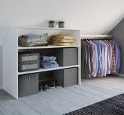 Weißes Regal- und Kleiderschrank-Organisationssystem unter einer Dachschräge mit gefalteten Textilien, grauen Aufbewahrungsboxen, Schuhen und hängenden Hemden; Perspektive: leicht seitliche Frontansicht von links auf Augenhöhe.