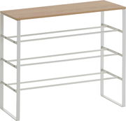 Schmales Schuhregal mit heller Holzablage und weißem Metallgestell mit drei Ebenen, freigestellt auf weißem Hintergrund, Ansicht schräg von vorne