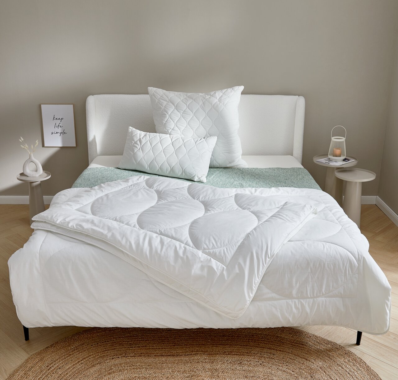 Gemütliches Schlafzimmer mit einem weißen Winterbett 155x220 cm, dekoriert mit passenden Kissen auf einem modernen Bettgestell. Frontalansicht.