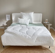 Gemütliches Schlafzimmer mit einem weißen Winterbett 155x220 cm, dekoriert mit passenden Kissen auf einem modernen Bettgestell. Frontalansicht.