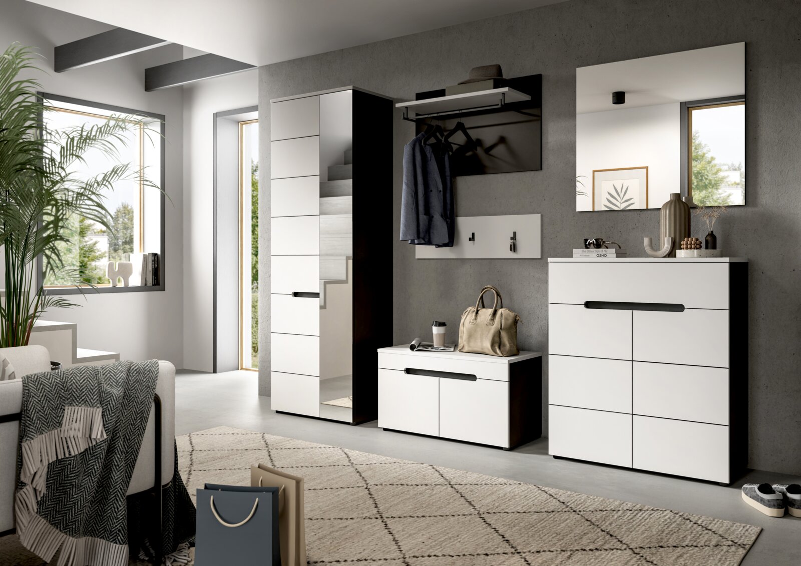 Modernes Flur-Set in Weiß mit schwarzen Griffleisten: hoher Garderobenschrank mit Spiegel, Schuhbank und Kommode sowie Wandgarderobe und Spiegel vor Betonwand, aufgenommen in leichter Schrägansicht von vorn.