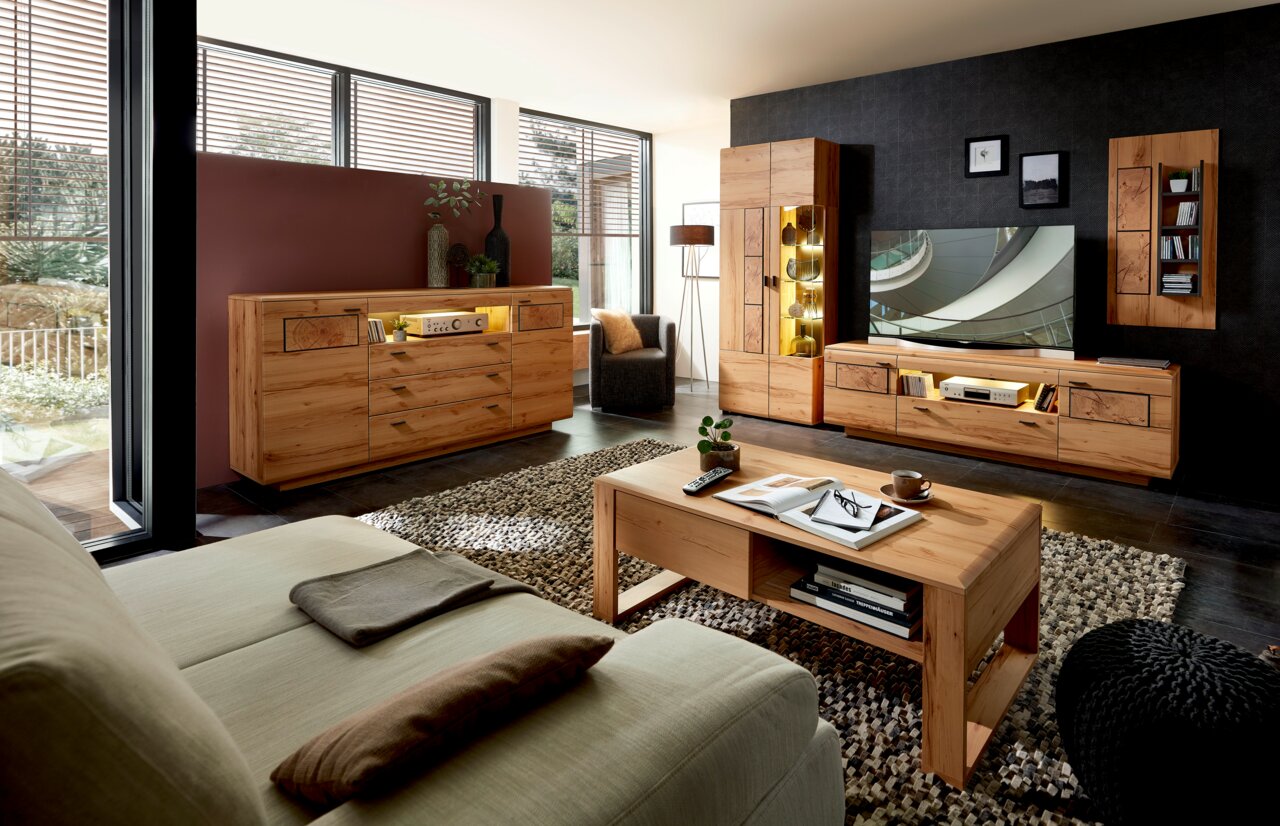 Moderne Wohnzimmermöbelkombination aus Holz mit LED-Beleuchtung, bestehend aus Sideboard, Wandregal und TV-Schrank, aus der Perspektive eines gemütlichen Wohnzimmers mit Sofa und Couchtisch.