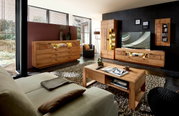 Moderne Wohnzimmermöbelkombination aus Holz mit LED-Beleuchtung, bestehend aus Sideboard, Wandregal und TV-Schrank, aus der Perspektive eines gemütlichen Wohnzimmers mit Sofa und Couchtisch.