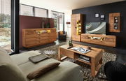 Moderne Wohnzimmermöbelkombination aus Holz mit LED-Beleuchtung, bestehend aus Sideboard, Wandregal und TV-Schrank, aus der Perspektive eines gemütlichen Wohnzimmers mit Sofa und Couchtisch.