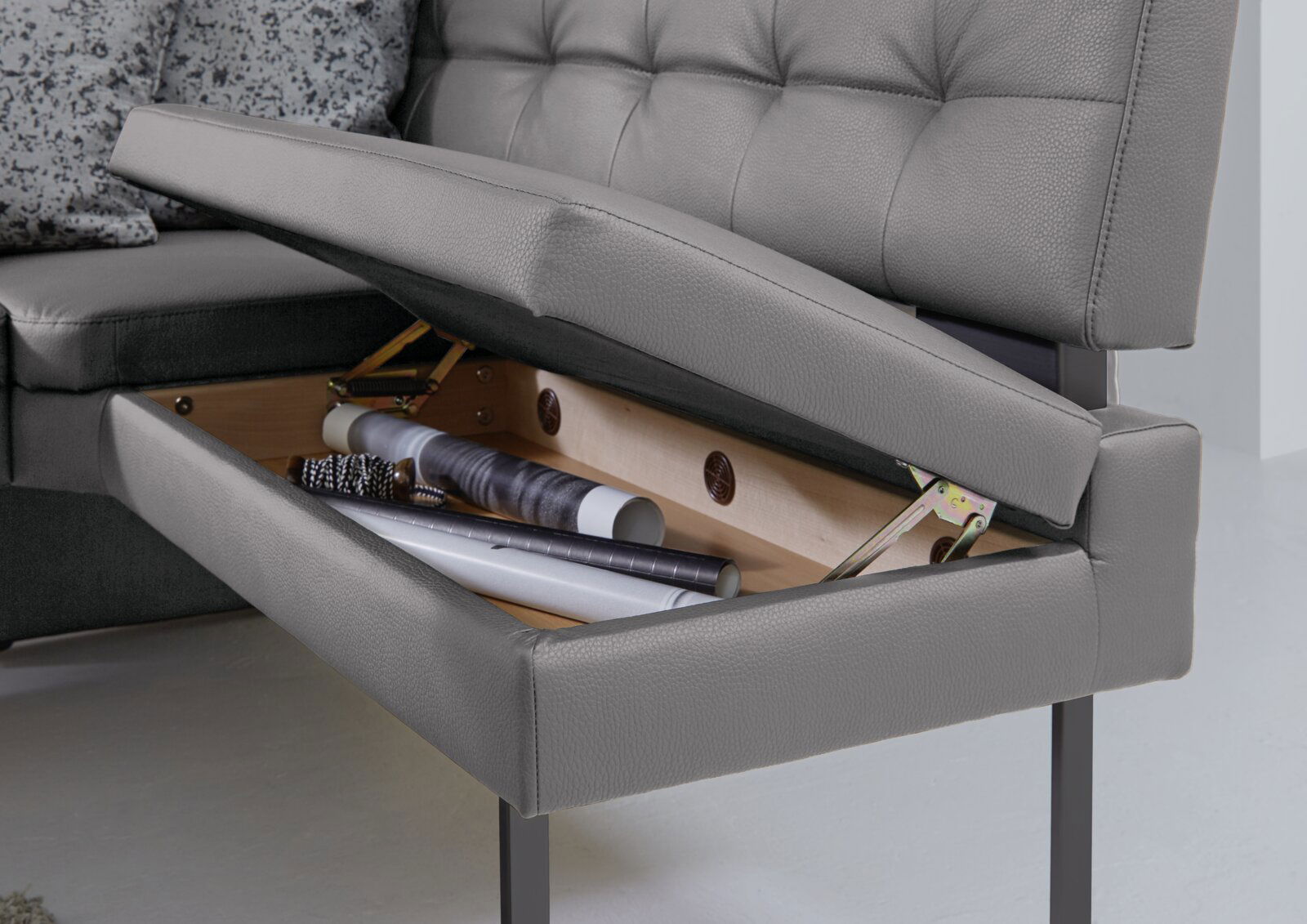 Dieter Knoll Eckbank LIMONE Graue Eckbank mit aufklappbarem Sitz, die Stauraum für verschiedene Gegenstände bietet. Perspektive von der Seite.