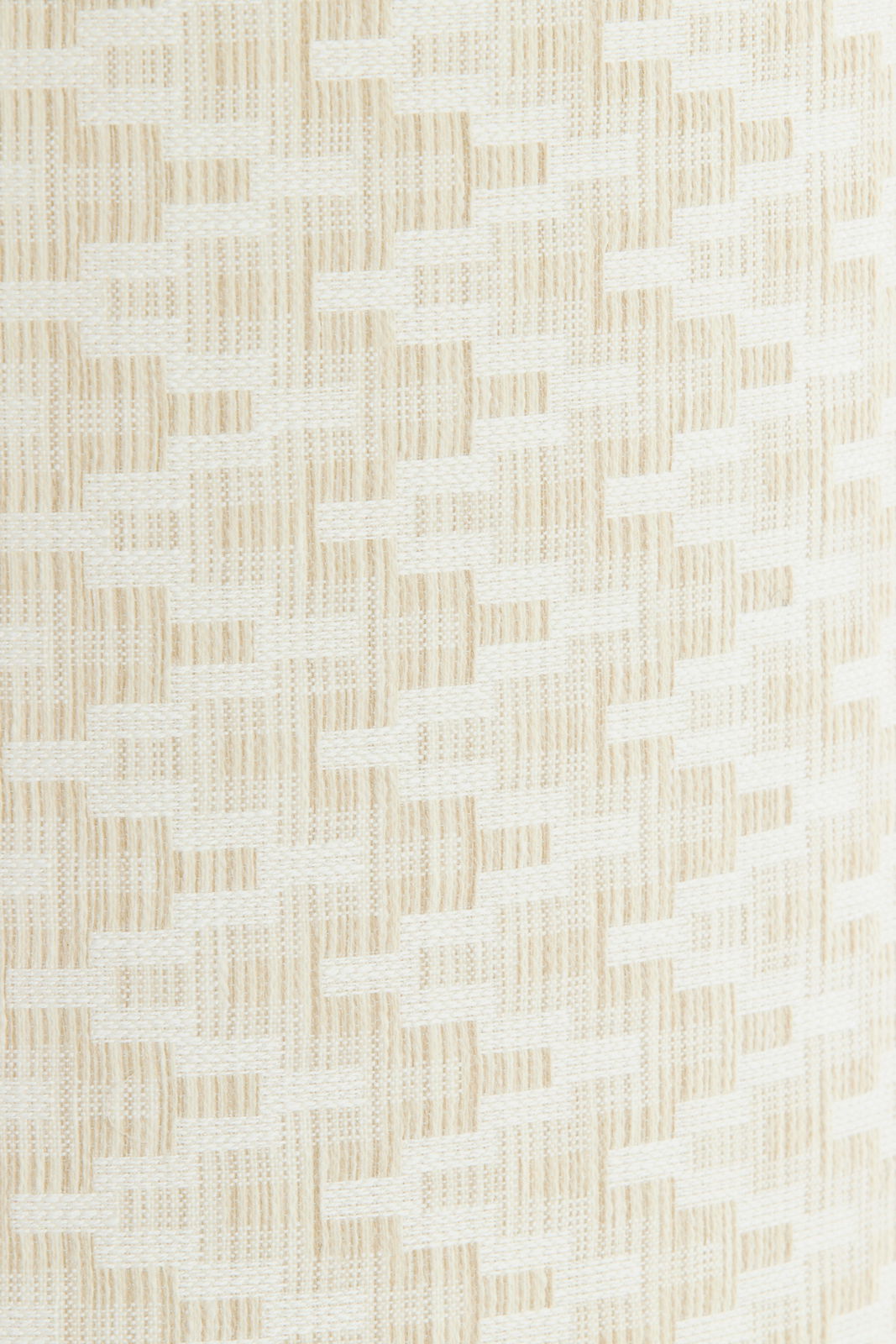 Nahaufnahme eines gewebten Lampenschirms mit beigem und weißem Muster, seitliche Perspektive