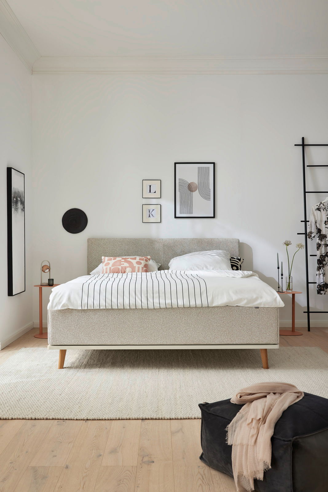 Frontale Ansicht eines modernen Polsterbetts MR DELPHI von Musterring in einem stilvoll eingerichteten Schlafzimmer mit dekorativen Kissen und minimalistischen Nachttischen.