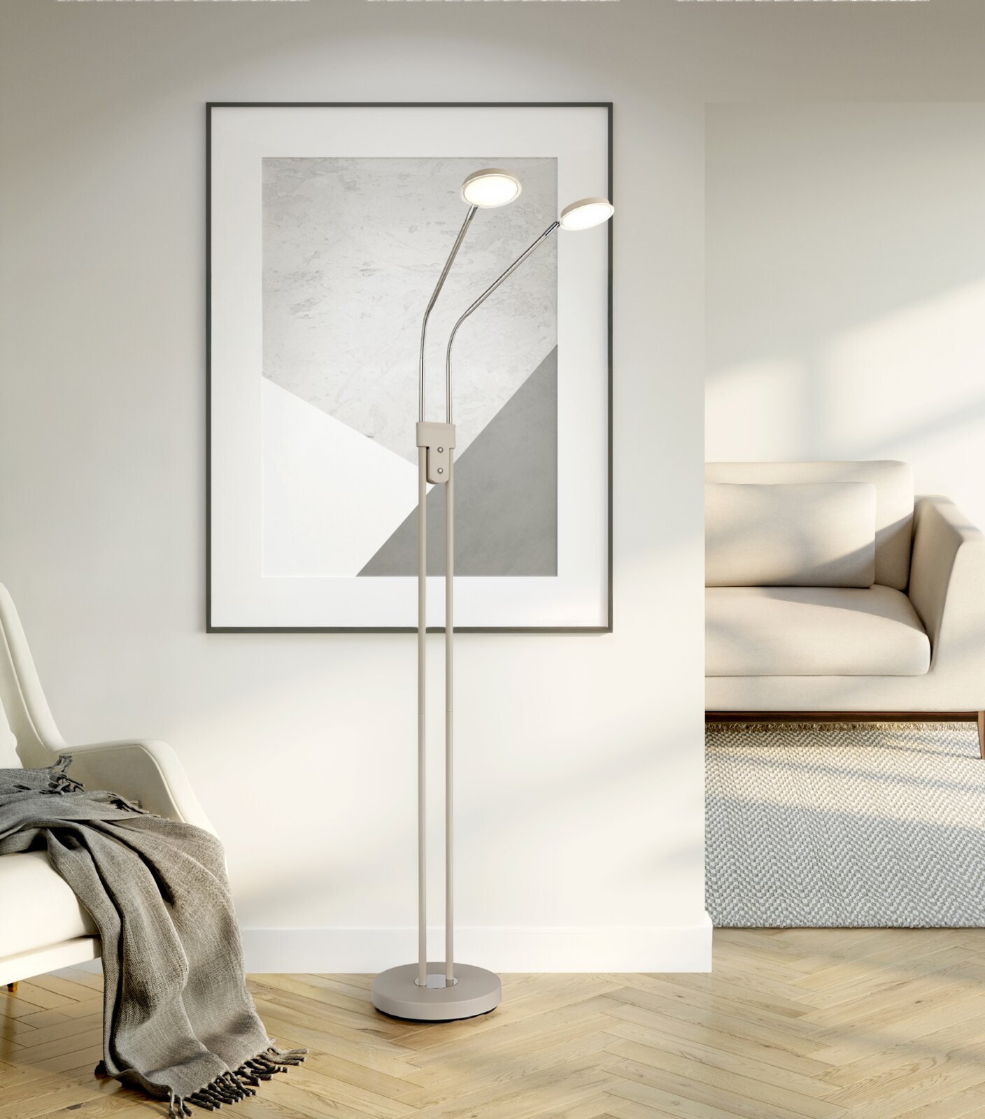 Moderne LED-Stehlampe in Beige mit zwei verstellbaren Leuchtenköpfen und rundem Standfuß, frontal in einem hellen Wohnzimmer neben Sofa und Wandbild aufgenommen.