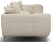 Beiges, gepolstertes Stoffsofa mit mehreren Rückenkissen und schmalen Metallfüßen, Seitenansicht von links leicht von hinten auf weißem Hintergrund
