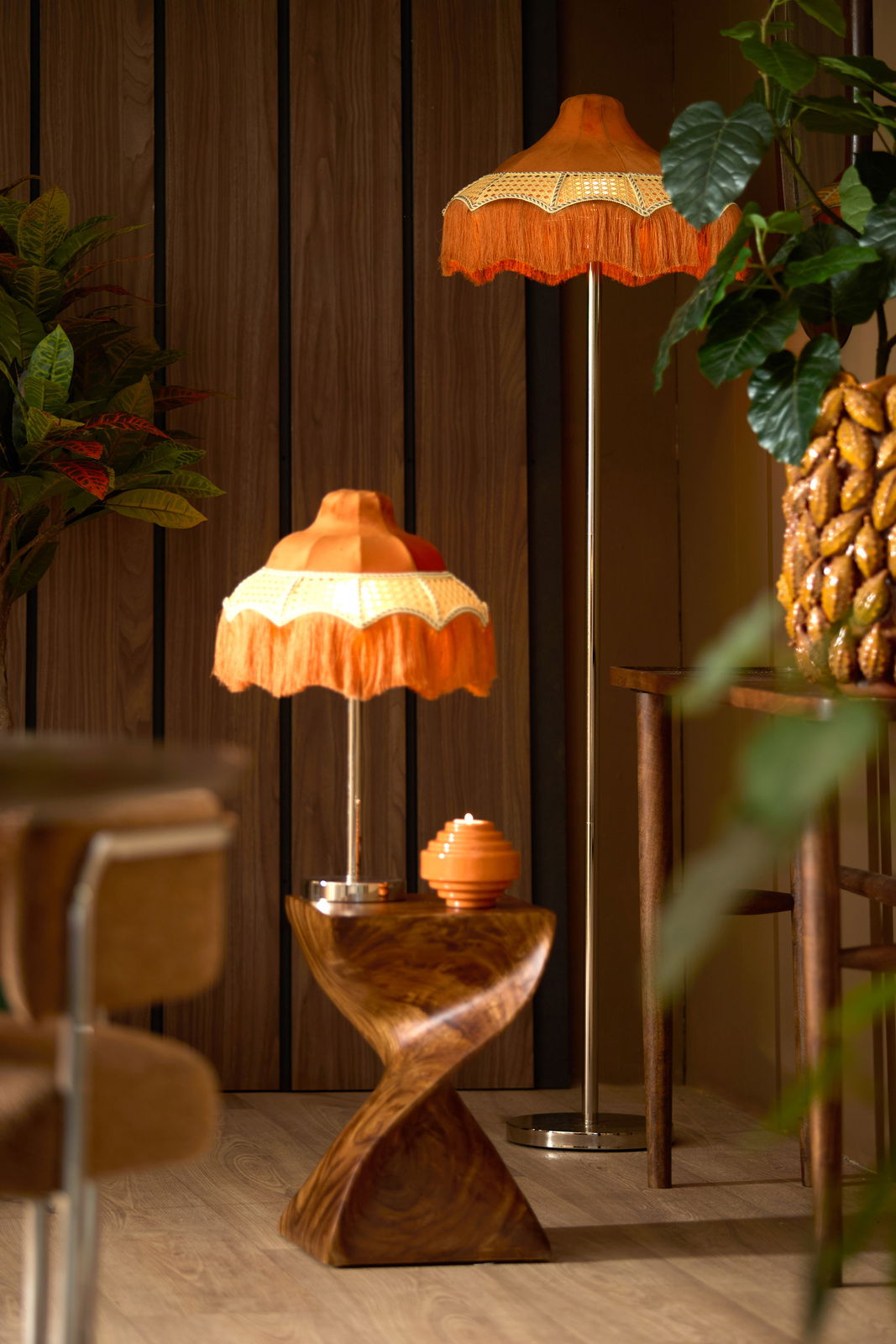Light&Living Stehleuchte WASHINGTON Retro Stehleuchte mit orangefarbenem Fransen-Lampenschirm, im Vordergrund aus seitlicher Perspektive fotografiert, umgeben von Holzmöbeln und Pflanzen.