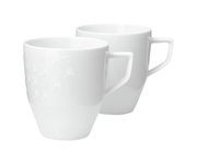 Zwei weiße Becher mit Henkel, einer mit dezentem Muster, aus seitlicher Perspektive fotografiert.