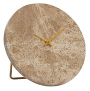 Close-up van een ronde klok van bruin marmer met gouden wijzers en minimalistische markeringen, gezien vanaf de zijkant.