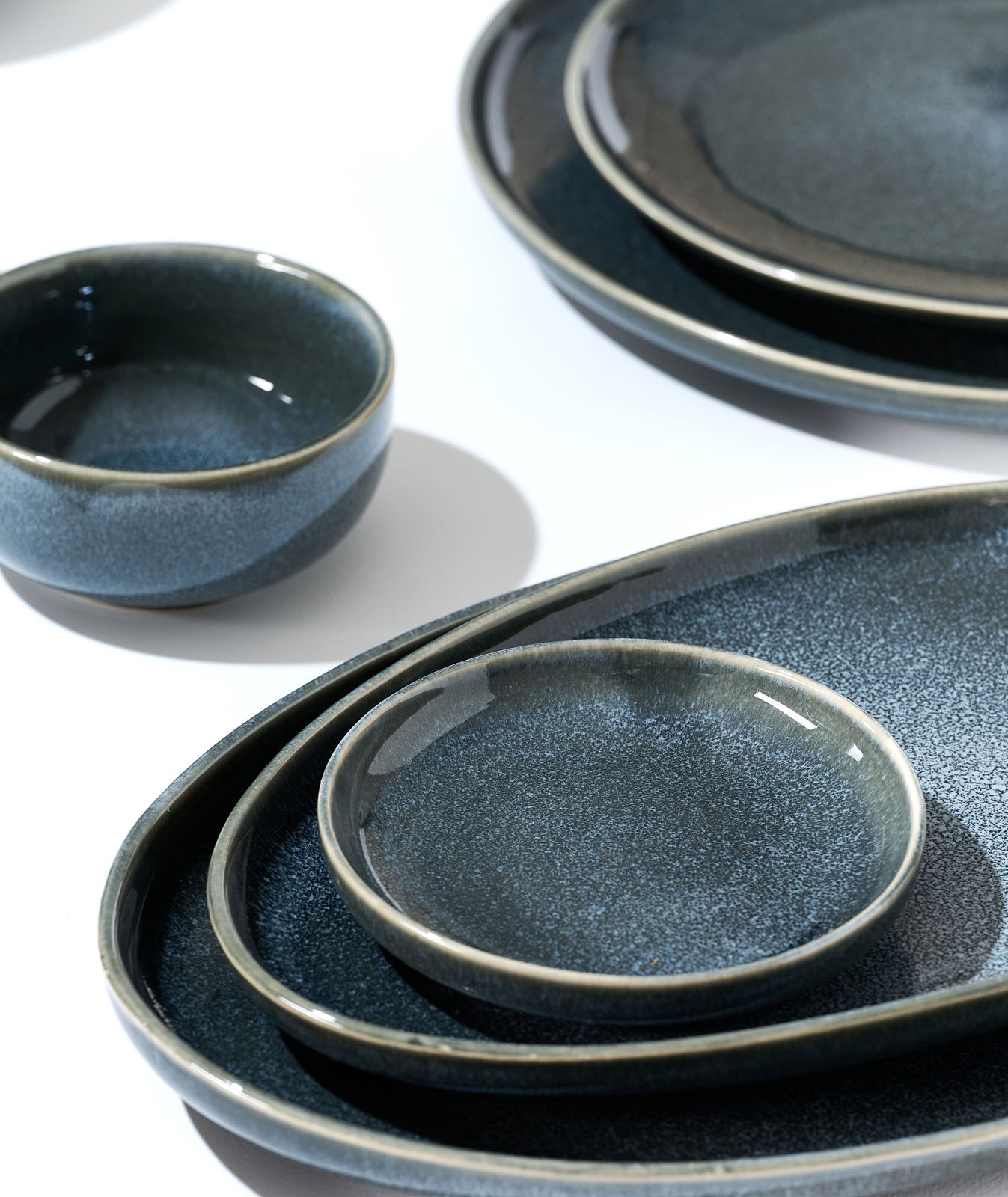 Ritzenhoff & Breker Müslischale EDA SCHIEFER Verschiedene dunkelblaue Keramikteller und Schalen in einer Nahaufnahme, von oben betrachtet, auf einem weißen Hintergrund arrangiert.