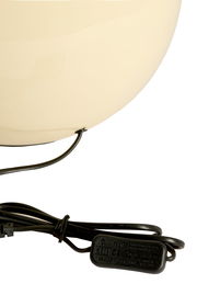 Nahaufnahme eines cremefarbenen Lampenfußes mit schwarzem Kabel und Schalter, seitliche Perspektive.