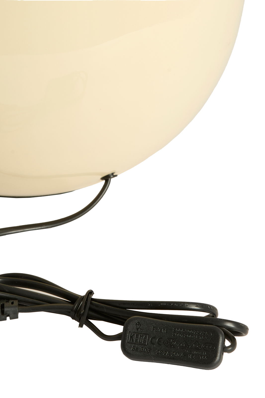 Nahaufnahme eines cremefarbenen Lampenfußes mit schwarzem Kabel und Schalter, seitliche Perspektive.