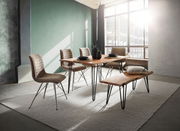 Moderner Essbereich mit Holztisch und Bank, umgeben von vier gepolsterten Stühlen, in einem lichtdurchfluteten Raum mit großen Fenstern, seitliche Perspektive.