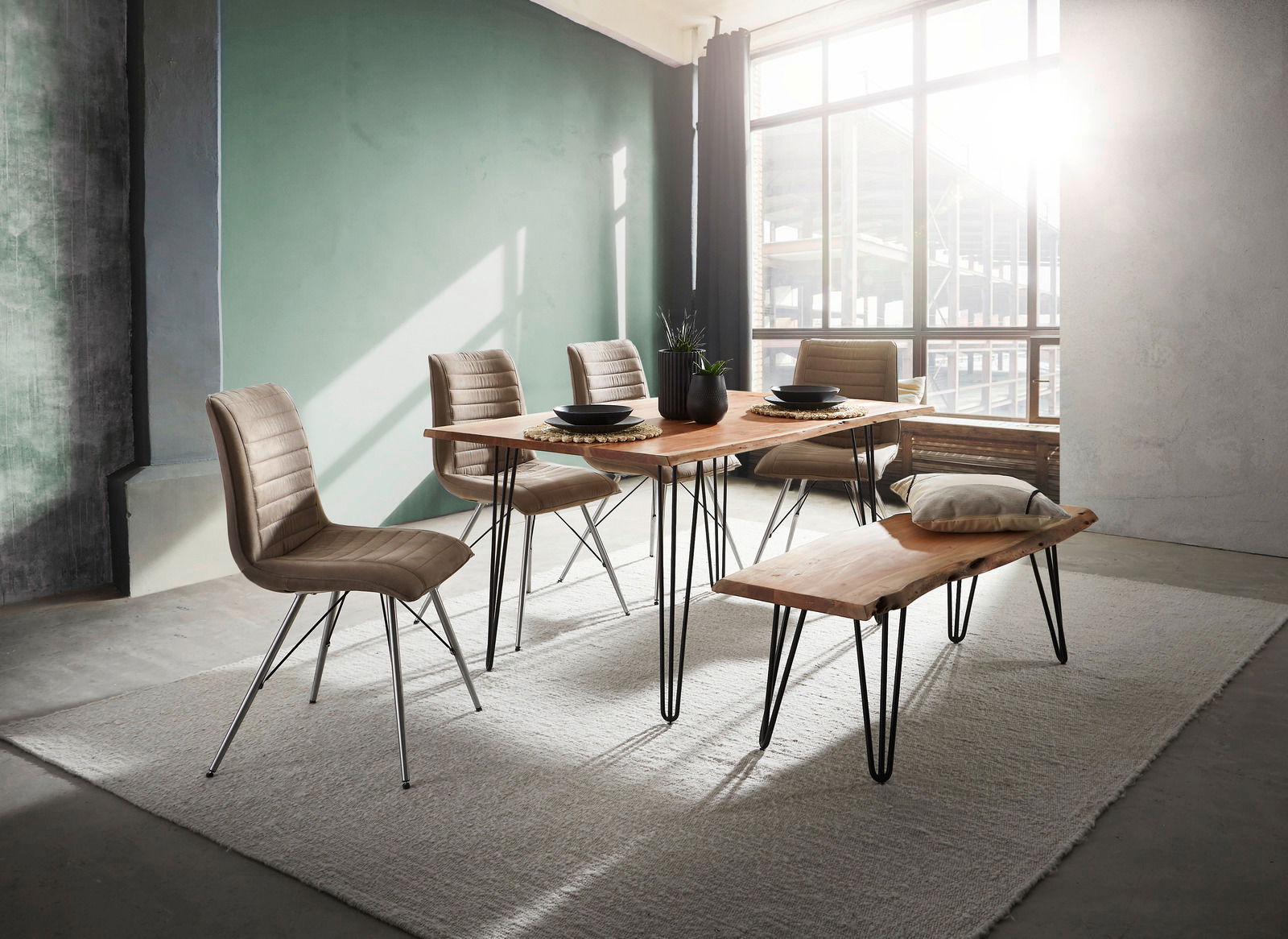 Moderner Essbereich mit Holztisch und Bank, umgeben von vier gepolsterten Stühlen, in einem lichtdurchfluteten Raum mit großen Fenstern, seitliche Perspektive.